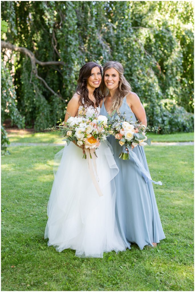 Bride and bridesmaid smile in the gardens at Blithewold Mansion venue in Rhode Island 