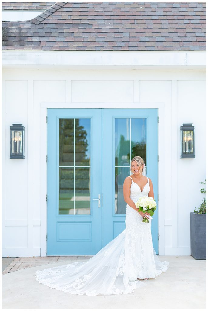 Bride poses with blue doors at Belle Mer Island House