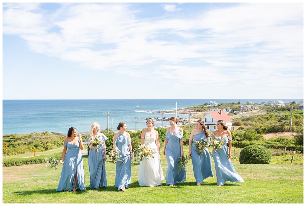 Bridesmaids walk on the back lawn of the spring house with ocean views behind them. 