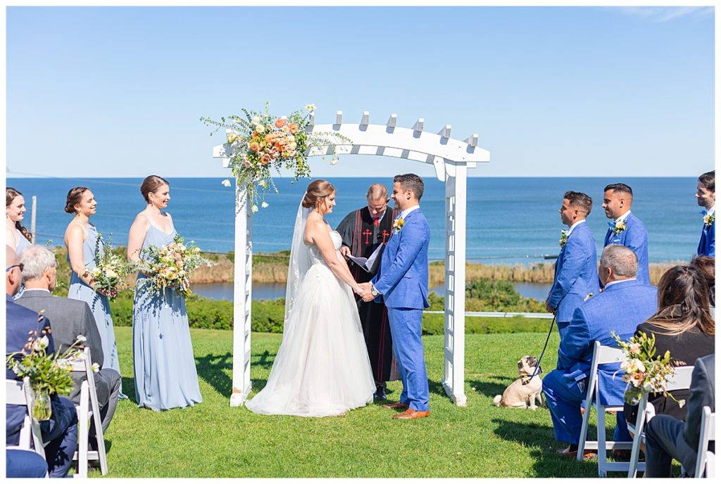 A bride and groom at their wedding ceremony on the front lawn at the spring house on block island. 