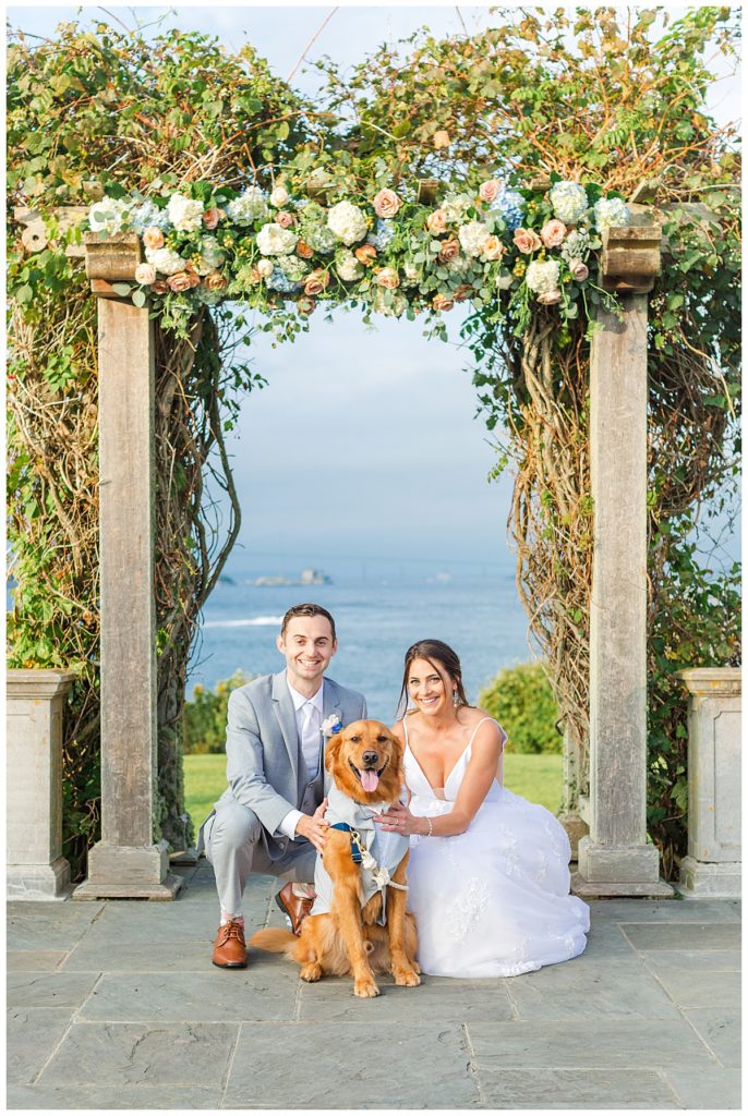 Bride and groom smile with their golden retriever after their wedding ceremony at Castle Hill Inn