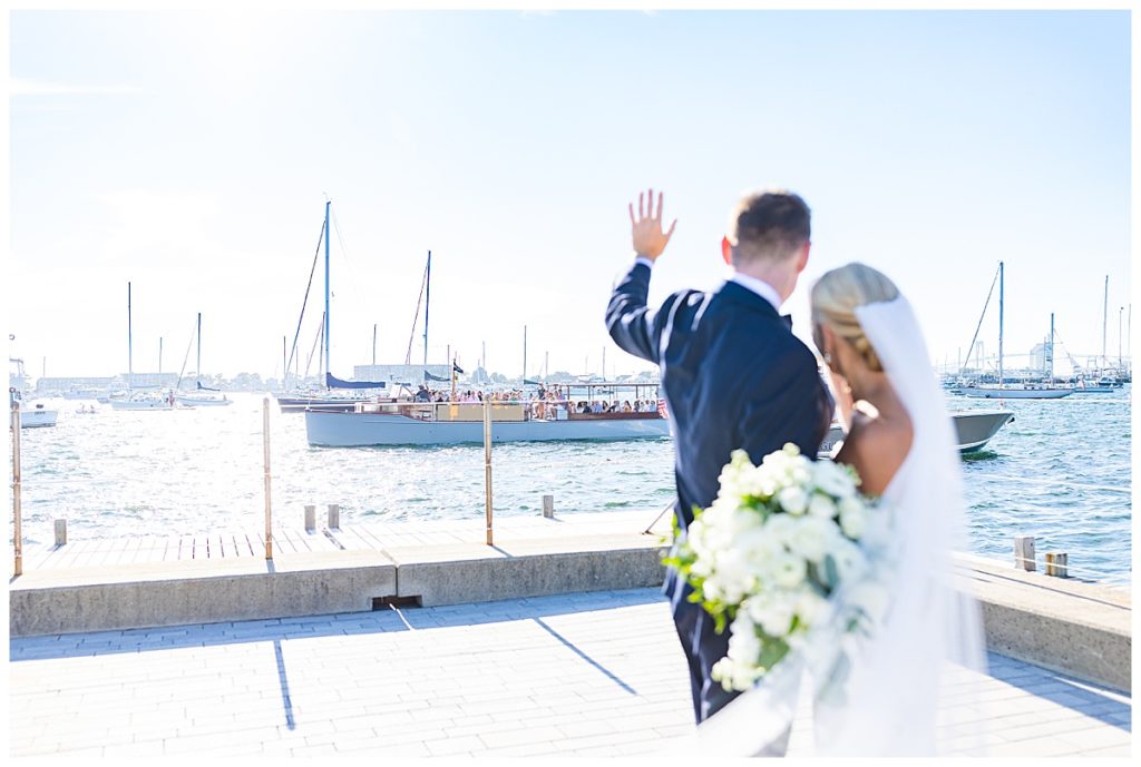 bride and groom waving at passing boats in Newport RI