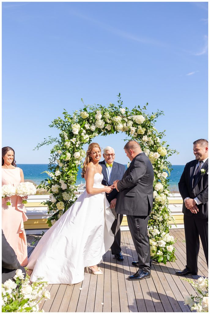 The bride and groom exchange rings during their wedding ceremony at Ocean House. 