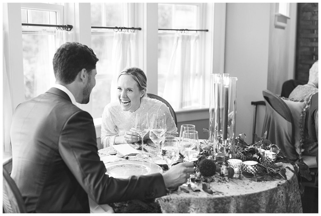 Bride and groom laugh at sweetheart table at dinner party reception at their weekapaug wedding. 