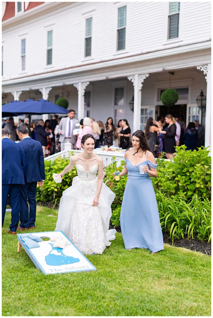 bride playing cornhole toss during cocktail hour at wedding