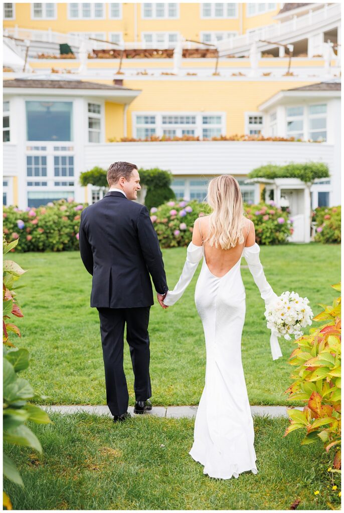 Bride and Groom walk through hydrangeas at Ocean house