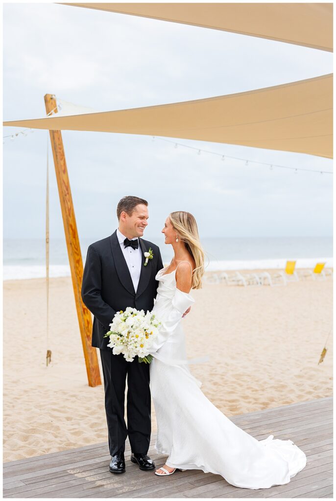 Bride and groom smile on the beach at Ocean House
