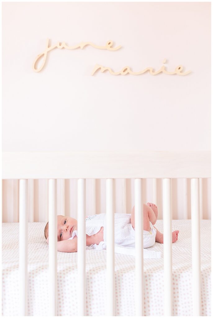 Baby lays in crib in nursery newborn session